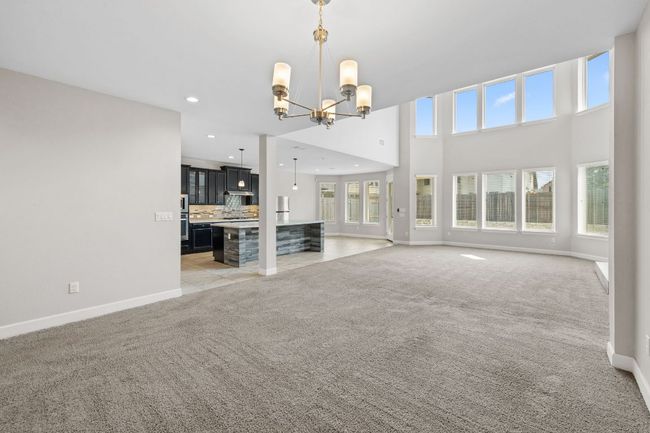 Unfurnished living room featuring baseboards, recessed lighting, an inviting chandelier, and light colored carpet | Image 11