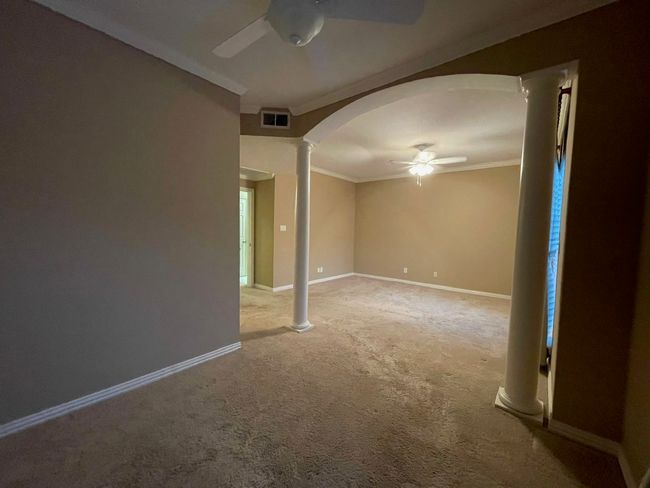 Carpeted empty room with ceiling fan, ornate columns, ornamental molding, and arched walkways | Image 13