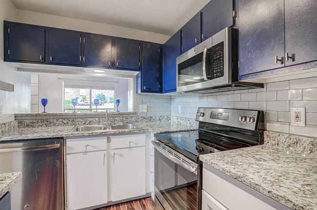 Kitchen with tasteful backsplash, a sink, appliances with stainless steel finishes, wood finished floors, and blue cabinetry | Image 9