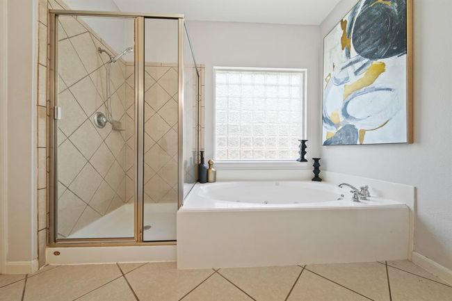 Enjoy the luxury of a spa-inspired jetted tub and separate glass-enclosed shower, all bathed in soft natural light from a glass block window. | Image 29