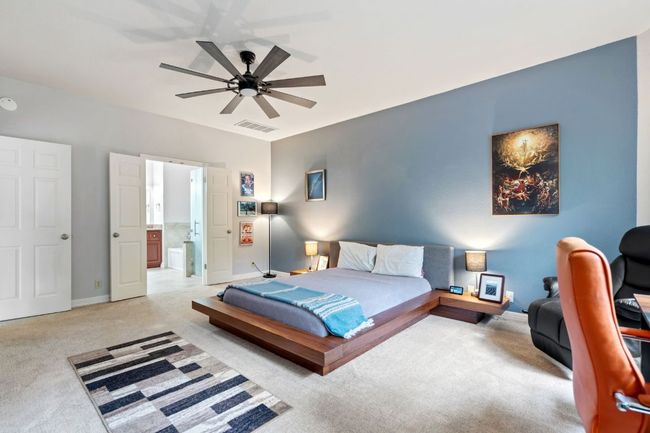 Bedroom featuring ensuite bathroom, ceiling fan, light carpet, baseboards, and visible vents | Image 23