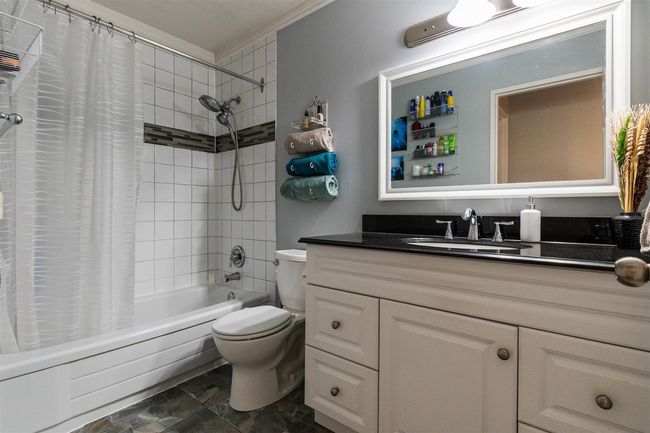 Bathroom featuring vanity, shower / bath combination with curtain, crown molding, and stone finish flooring | Image 19