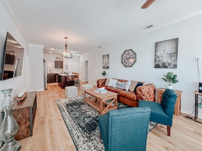 Living room with light wood finished floors, visible vents, ornamental molding, a textured ceiling, and baseboards | Image 10