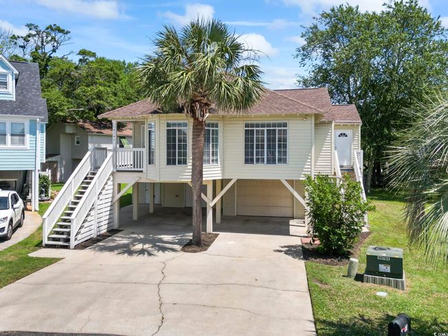 Beach home featuring stairway, driveway, a carport, and a shingled roof | Image 4