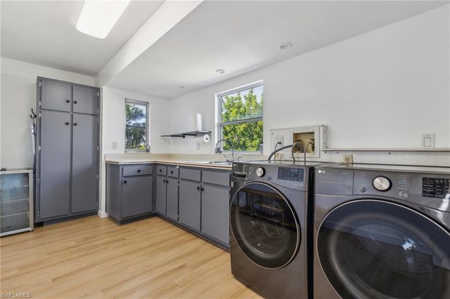 Laundry room featuring washer and dryer, light wood-type flooring, a sink, and cabinet space | Image 30
