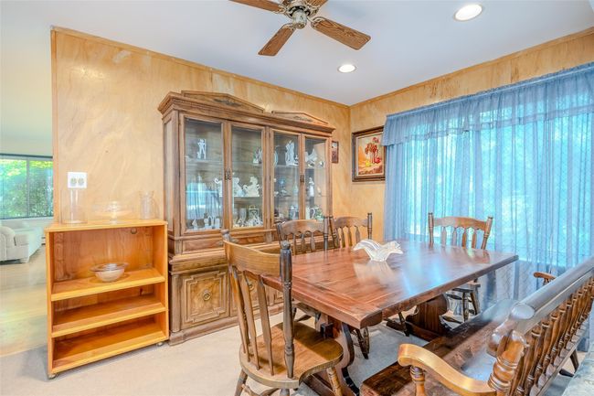 Dining area featuring a ceiling fan, light colored carpet, baseboard heating, and a stone fireplace | Image 12