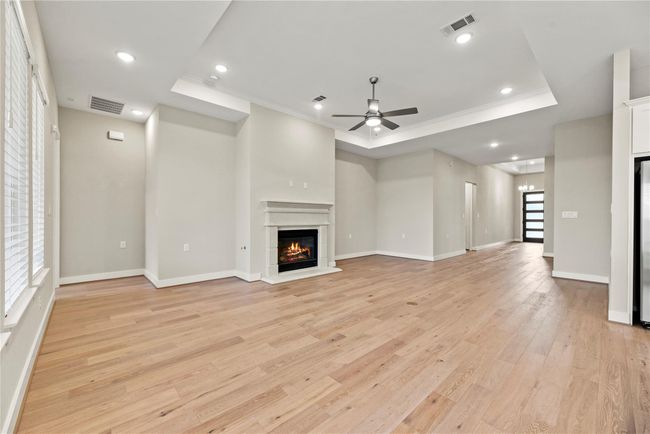 The family room offers ample space for all of your favorite furnishings, featuring durable LVP flooring, a raised tray ceiling with recessed lighting and a modern fan, and the crowning touch, a romantic gas-log fireplace that sets a warm and inviting tone. | Image 10