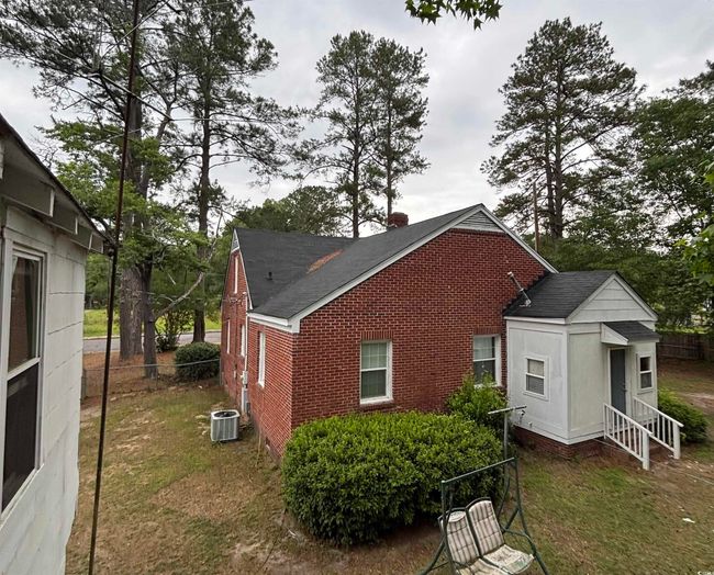 View of side of home with brick siding, a shingled roof, and entry steps | Image 5