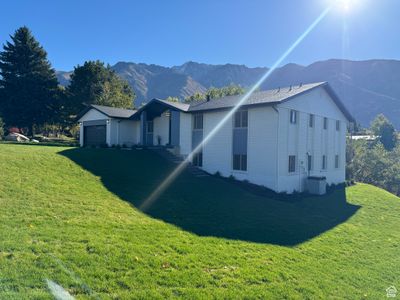 View of front of property with central air condition unit, a mountain view, a front lawn, and a garage | Image 1