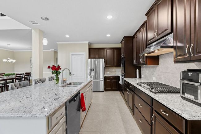 Kitchen featuring appliances with stainless steel finishes, exhaust hood, a sink, ornamental molding, and tasteful backsplash | Image 10