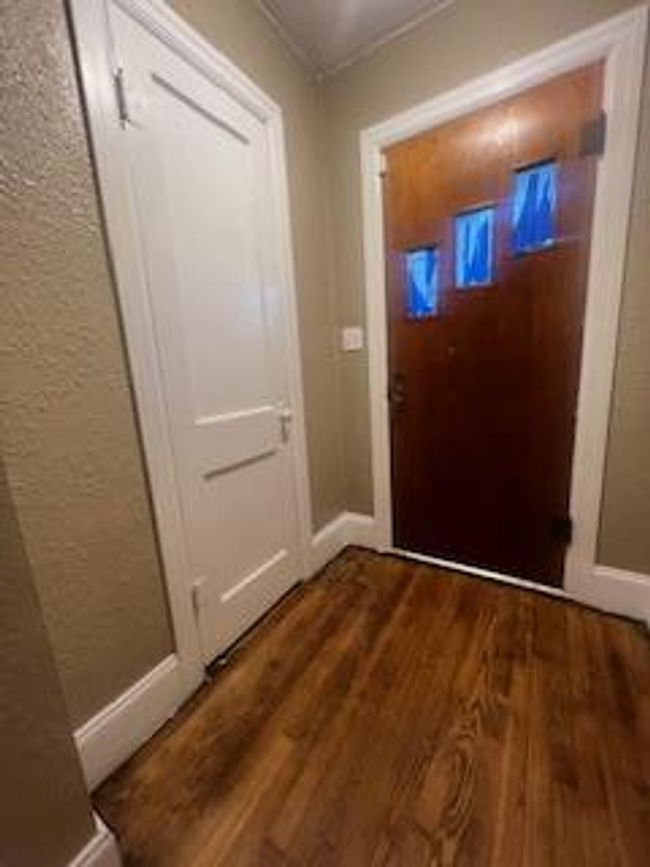 Doorway with dark wood-style flooring, a textured wall, and baseboards | Image 6