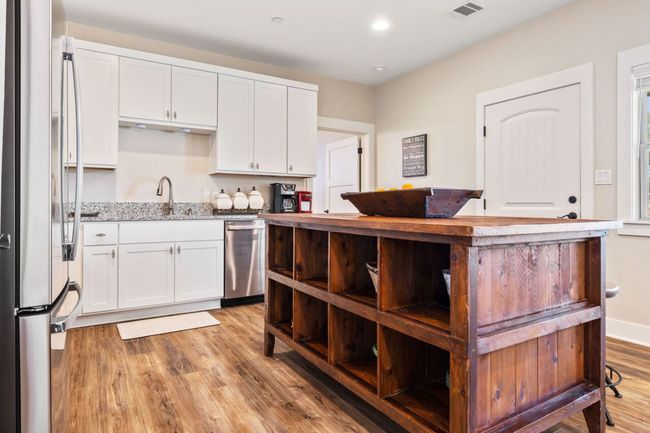 Kitchen featuring appliances with stainless steel finishes, light wood-type flooring, white cabinetry, light stone counters, and recessed lighting | Image 32