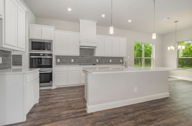 Kitchen featuring stainless steel appliances, decorative backsplash, light countertops, a chandelier, and recessed lighting | Image 8