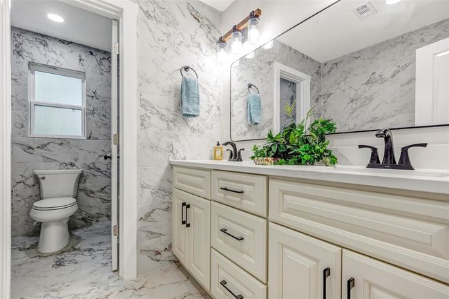 Secondary bathroom with double sink, new shower and tub, new cabinets and light fixtures. | Image 34