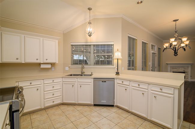 Kitchen with stainless steel appliances, a sink, a chandelier, a peninsula, and ornamental molding | Image 7
