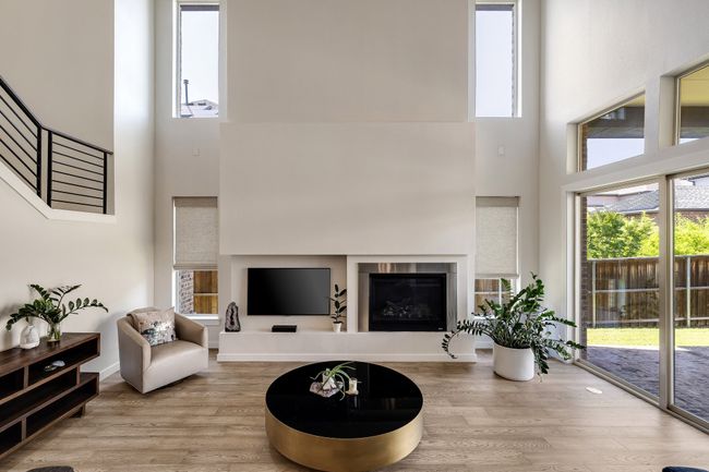 Living room featuring a high ceiling, wood finished floors, plenty of natural light, and a glass covered fireplace | Image 15