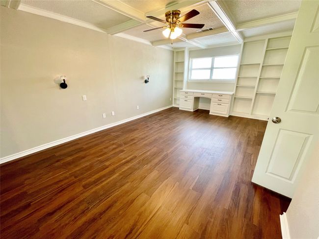 Unfurnished bedroom featuring dark wood finished floors, visible vents, baseboards, built in desk, and coffered ceiling | Image 16