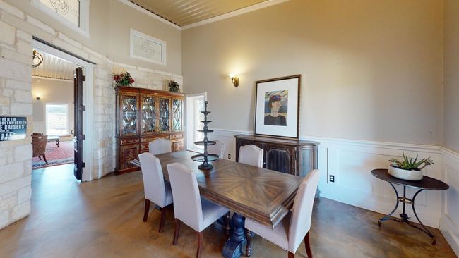 Dining area with a decorative wall, a high ceiling, finished concrete flooring, wainscoting, and crown molding | Image 11