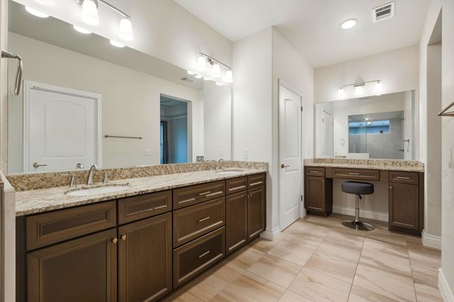 Primary Bathroom with tiled shower, double vanity, tile floor, separate make-up vanity with drawers and cabinets. | Image 15