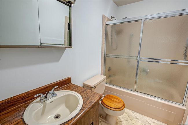 Full bathroom featuring toilet, bath / shower combo with glass door, and sink | Image 9