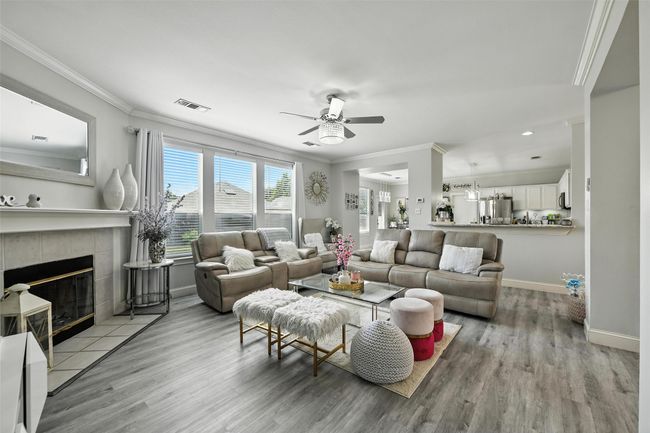 Living area featuring crown molding, a ceiling fan, light wood-style flooring, a fireplace, and recessed lighting | Image 11