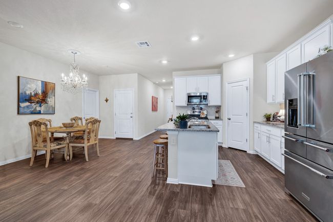 Kitchen with white cabinets, dark wood-type flooring, visible vents, and appliances with stainless steel finishes | Image 6