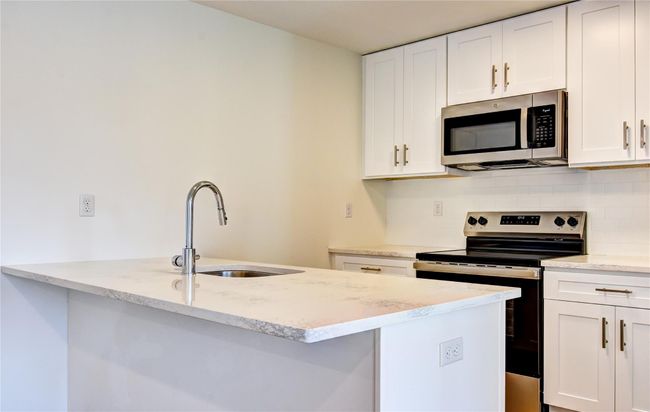 Kitchen with a sink, light stone counters, backsplash, stainless steel appliances, and white cabinets | Image 33