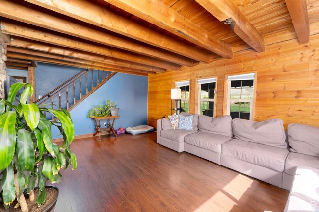 Living room featuring wooden walls, beamed ceiling, wood finished floors, stairway, and wood ceiling | Image 19
