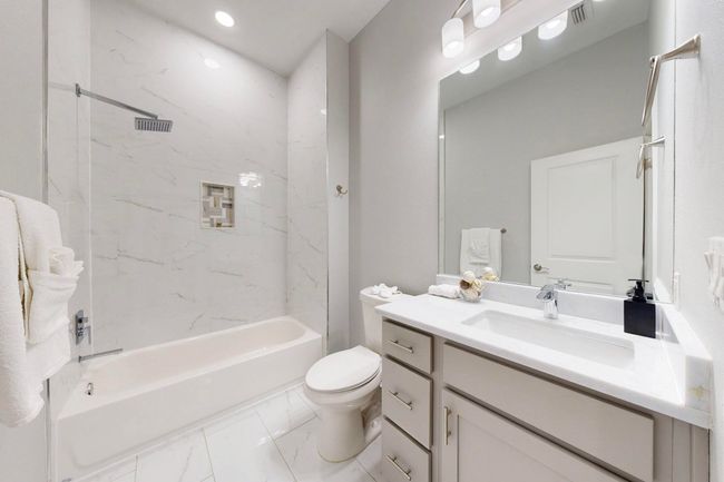 Bathroom with vanity, marble look tile flooring, washtub / shower combination, toilet, and recessed lighting | Image 10