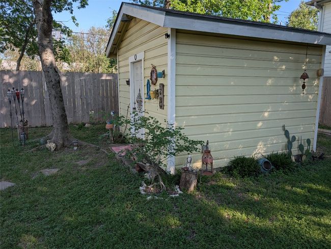 View of side of home with fence, an outdoor structure, and a yard | Image 22