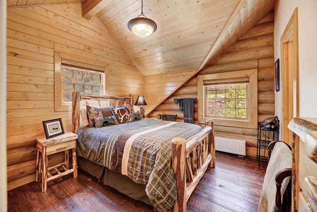 Bedroom featuring radiator heating unit, dark wood-type flooring, log walls, and wooden ceiling | Image 30