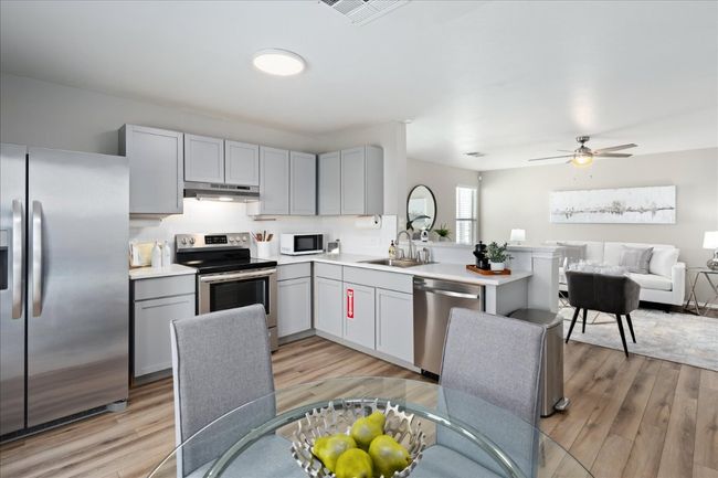 Kitchen featuring gray cabinets, under cabinet range hood, a sink, stainless steel appliances, and light wood finished floors | Image 12