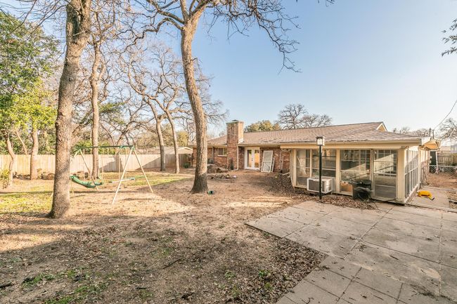 Back of property featuring a chimney, a fenced backyard, a sunroom, a playground, and a patio area | Image 22