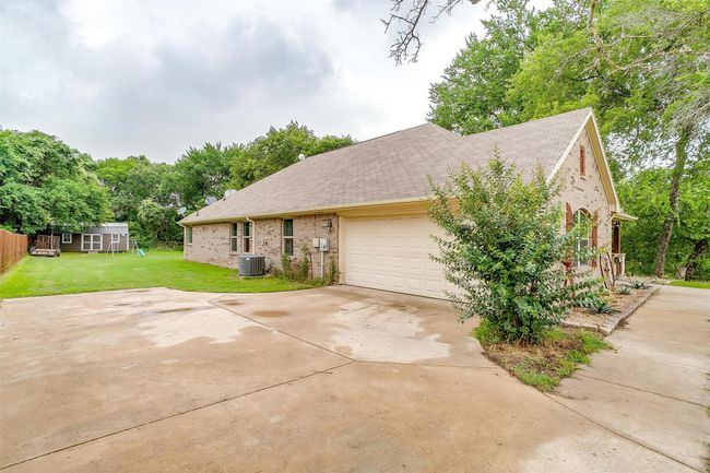 View of front of home featuring brick siding, roof with shingles, a front yard, a garage, and driveway | Image 7