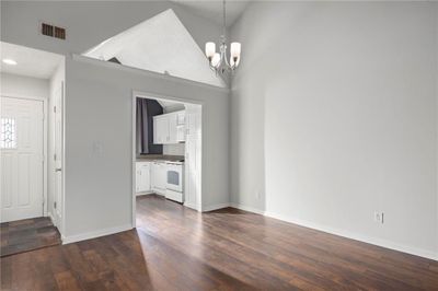 Unfurnished living room featuring high vaulted ceiling, a notable chandelier, a textured ceiling, and dark hardwood / wood-style flooring | Image 3