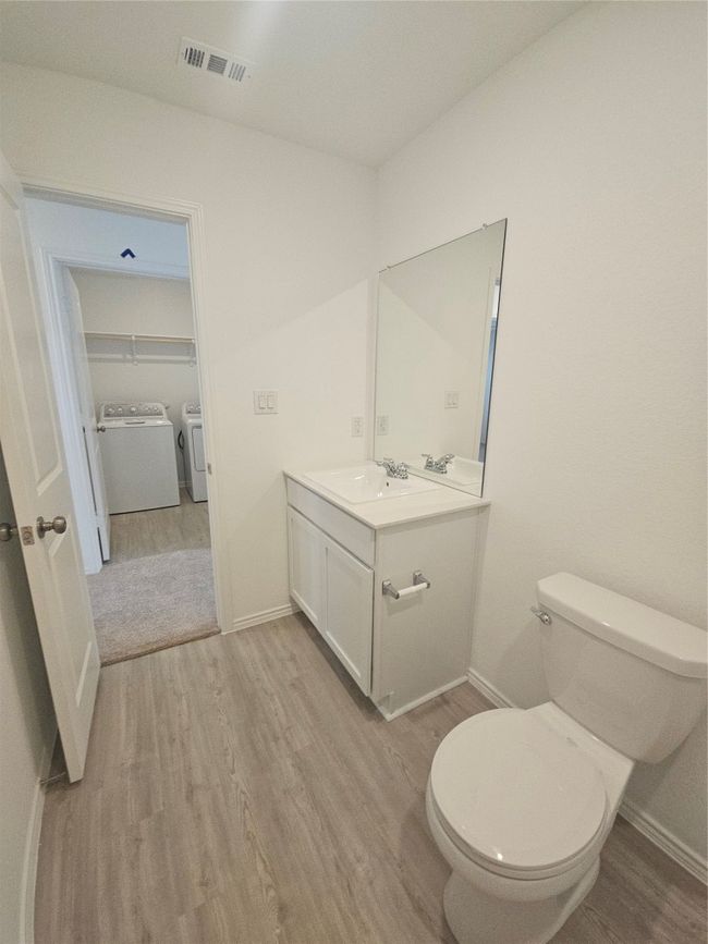 Bathroom with washer and dryer, wood finished floors, vanity, toilet, and baseboards | Image 9