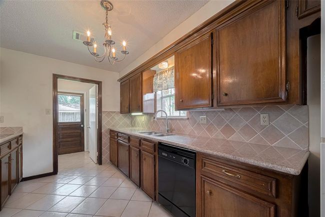 Elegant kitchen with rich wooden cabinetry, sleek granite countertops, and ceramic tile flooring. | Image 9