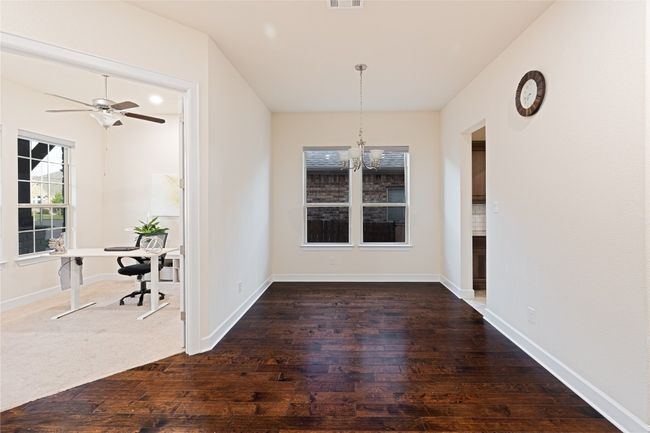 Unfurnished dining area with a chandelier, wood-type flooring, a desk, and ceiling fan | Image 8