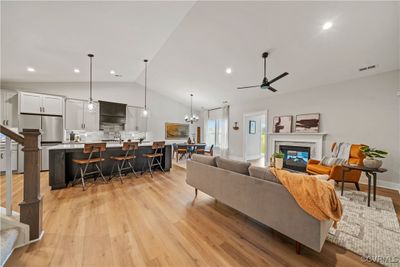 Living room with light wood-type flooring, ceiling fan with notable chandelier, and lofted ceiling | Image 2