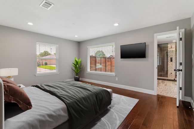 The primary bedroom is a peaceful retreat with engineered wood floors, canned lighting and large pictures windows to allow for plenty of sunshine or night skies. *Virtually staged photo* | Image 16