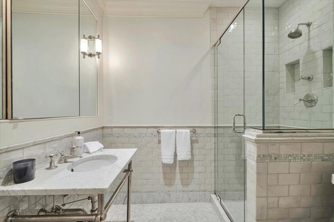 Elegant lower level full bath featuring a shower stall, tile walls, and ornamental molding. | Image 26