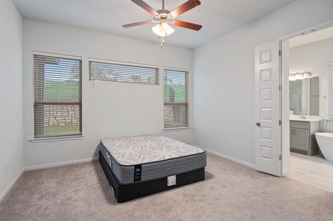 Bedroom with baseboards, ensuite bath, ceiling fan, and light carpet | Image 15