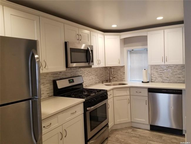 Kitchen with appliances with stainless steel finishes, a sink, light countertops, white cabinets, and recessed lighting | Image 8