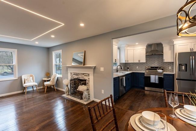Kitchen featuring white cabinets, a sink, wall chimney range hood, stainless steel appliances, and blue cabinetry | Image 35
