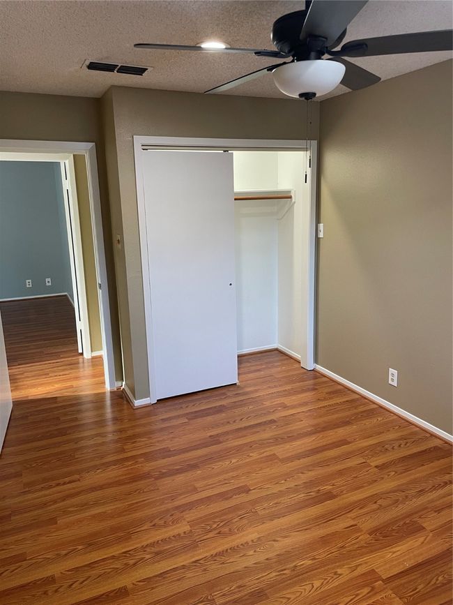 Unfurnished bedroom featuring ceiling fan, wood-type flooring, a closet, and a textured ceiling | Image 19