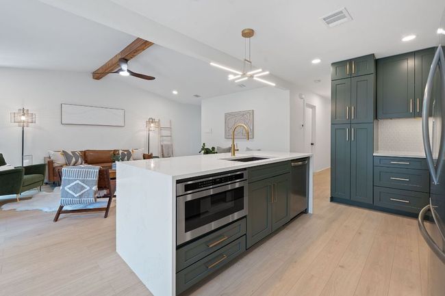 Kitchen with stainless steel dishwasher, light countertops, light wood-type flooring, a ceiling fan, and recessed lighting | Image 11