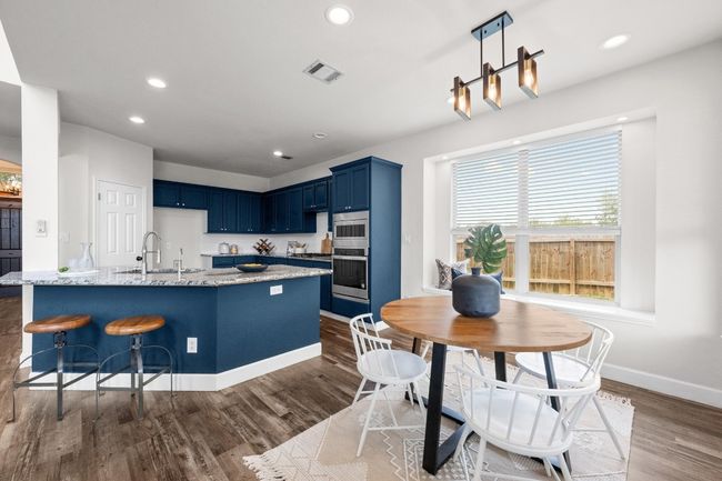 Kitchen featuring blue cabinets, dark wood-style flooring, light stone counters, a sink, and baseboards | Image 11