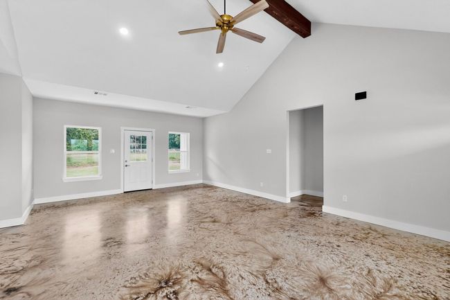 Unfurnished living room featuring high vaulted ceiling, beamed ceiling, a ceiling fan, recessed lighting, and finished concrete floors | Image 15