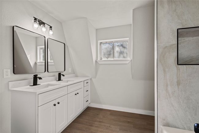 Full bathroom with double vanity, baseboards, a sink, and wood finished floors | Image 19