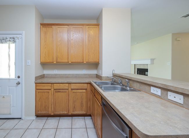 Kitchen with dishwasher, a peninsula, a fireplace, light countertops, and light tile patterned flooring | Image 14